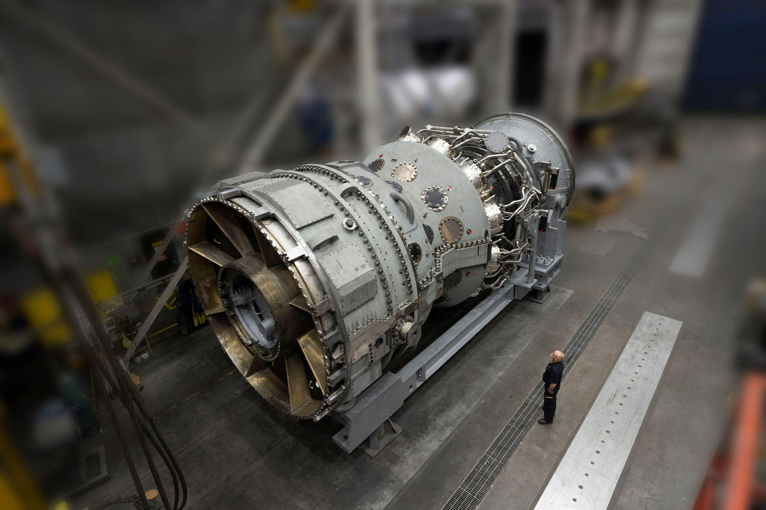 GE Vernova’s 7HA.03 gas turbine on a stand in the Greenville factory, with a person beside it for scale.