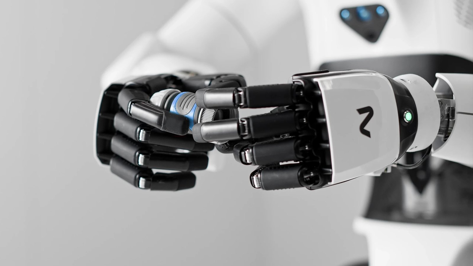 A white and black NEURA robot hand holding a small cylindrical part.