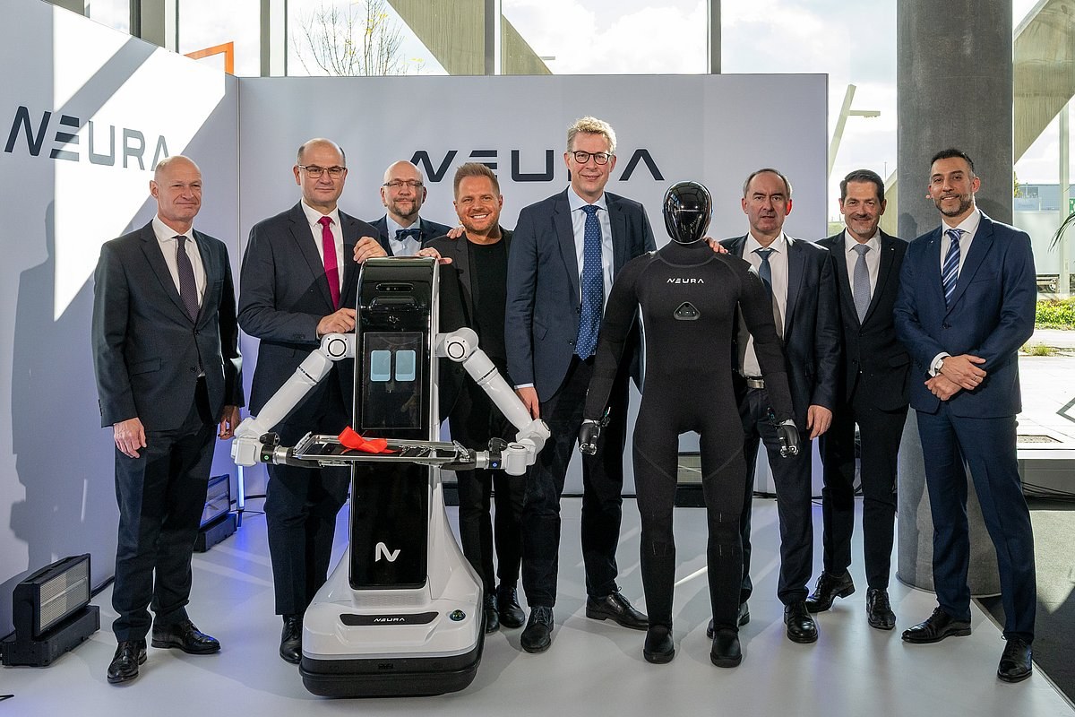 Officials and a humanoid robot at the opening of the TUM RoboGym, with a NEURA machine beside them.
