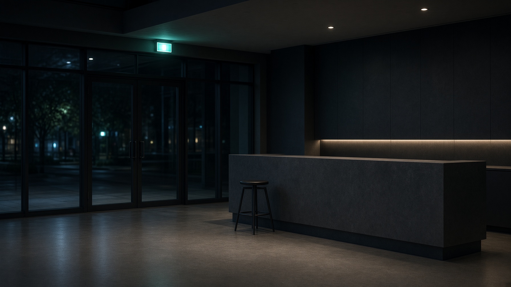 An empty lobby at night, with a reception desk, a stool and glass doors.
