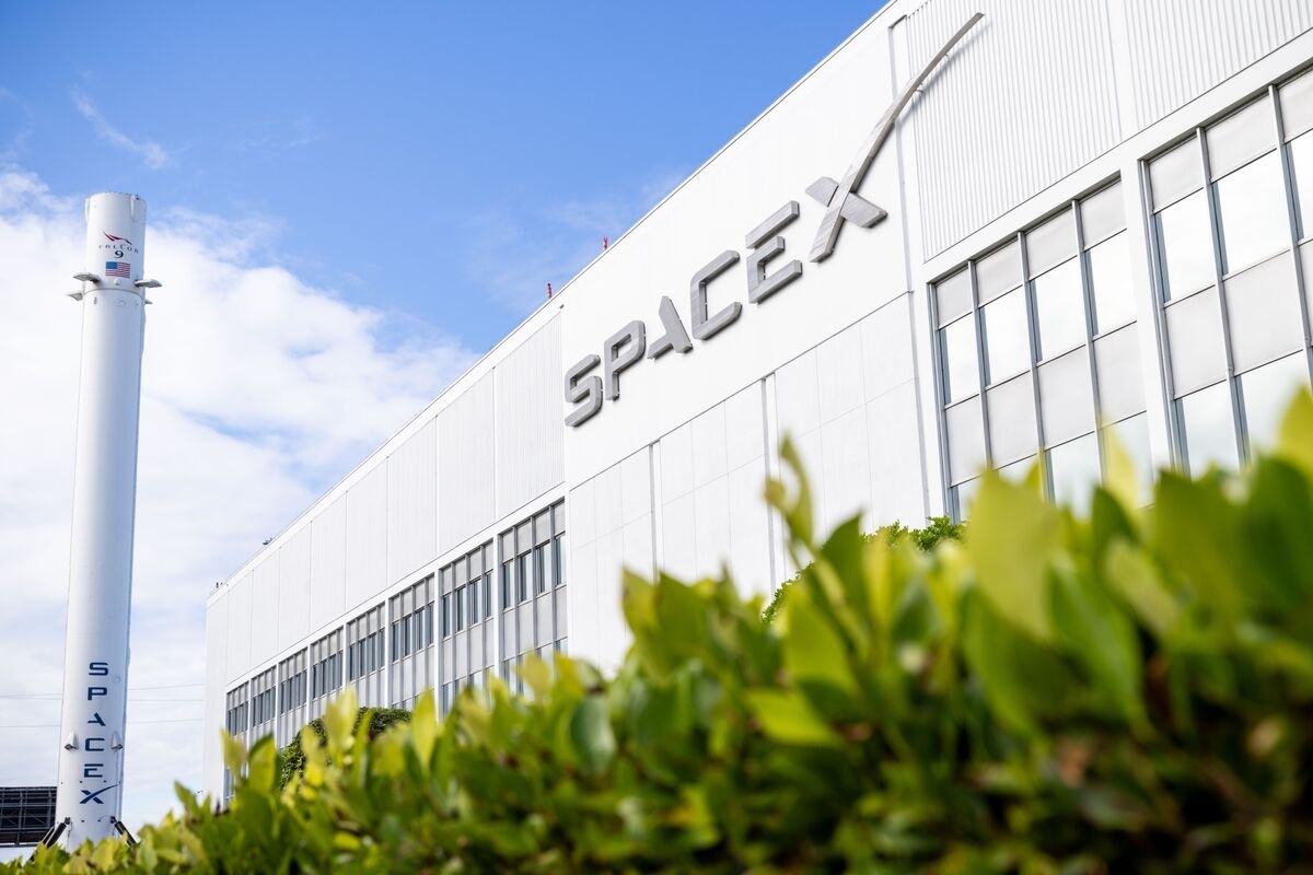 A SpaceX building and a rocket stage against a blue sky.